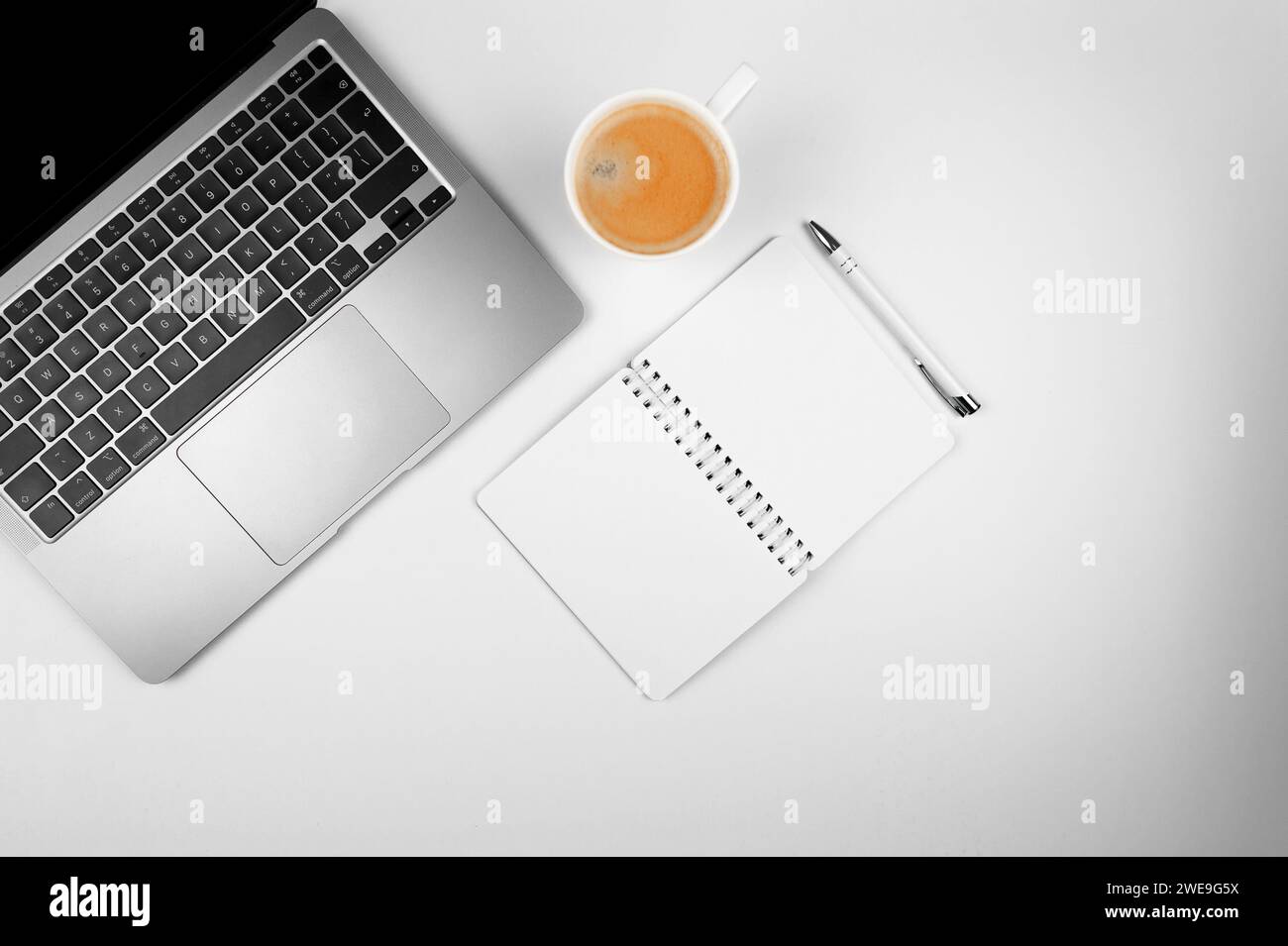 Top view of grey laptop computer on white background. Notebook, pen and coffee cup flat lay, copy space. Stock Photo