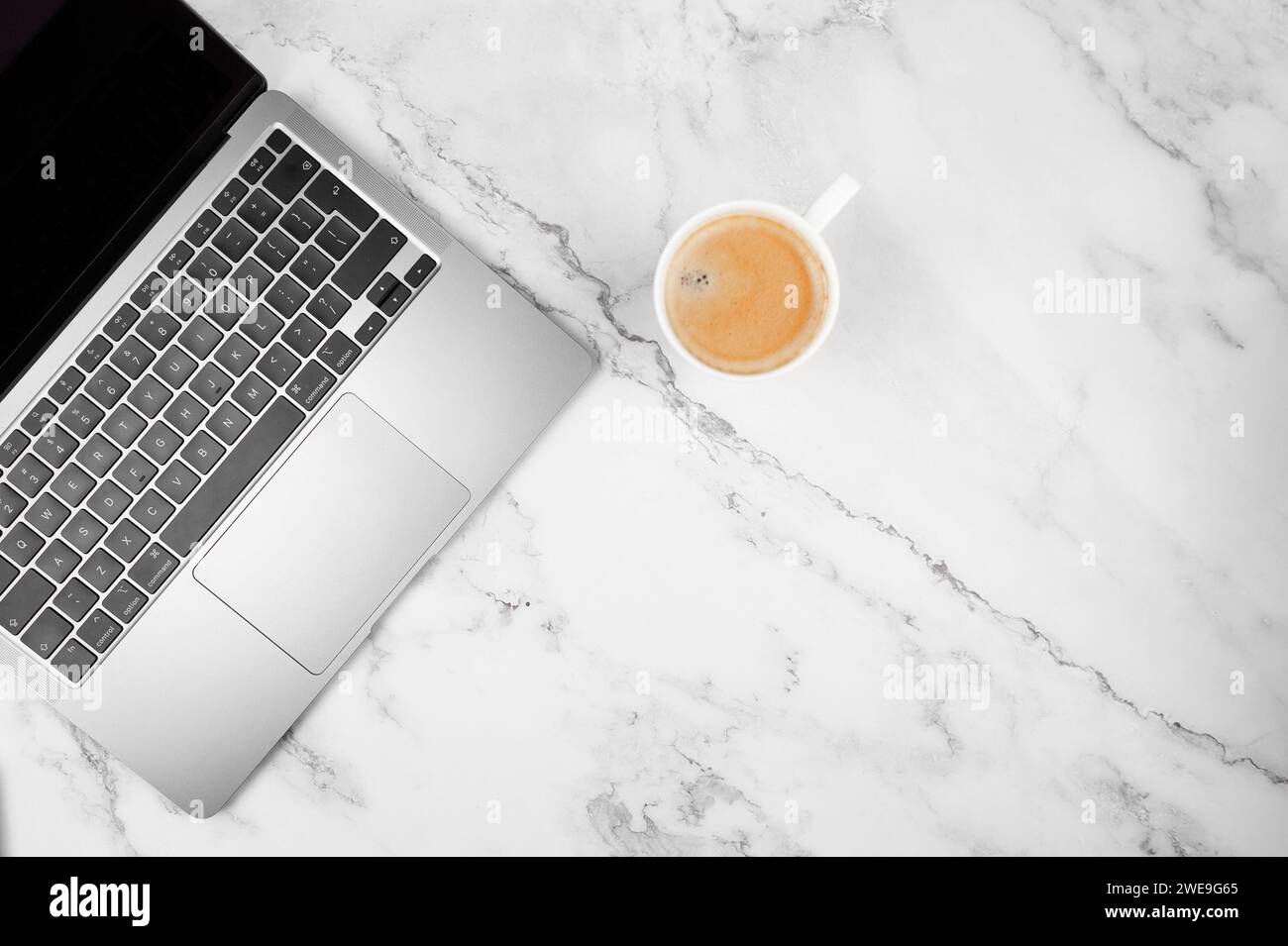Top view of grey laptop computer on white marble background. Coffee cup, flat lay, copy space. Stock Photo