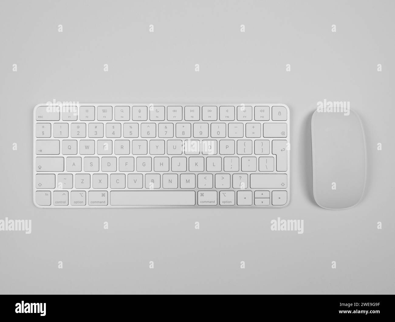 Top view of white keyboard and mouse on light grey background. Modern office flat lay, copy space. Stock Photo