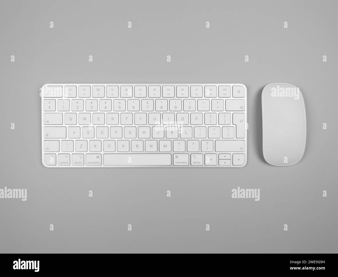 Top view of white keyboard and mouse on light grey background. Modern office flat lay, copy space. Stock Photo