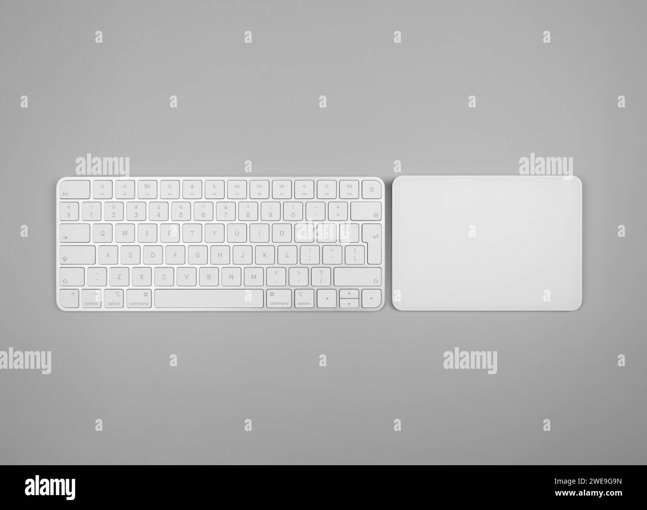 Top view of white keyboard, touchpad on light grey background. Modern office flat lay, copy space. Stock Photo