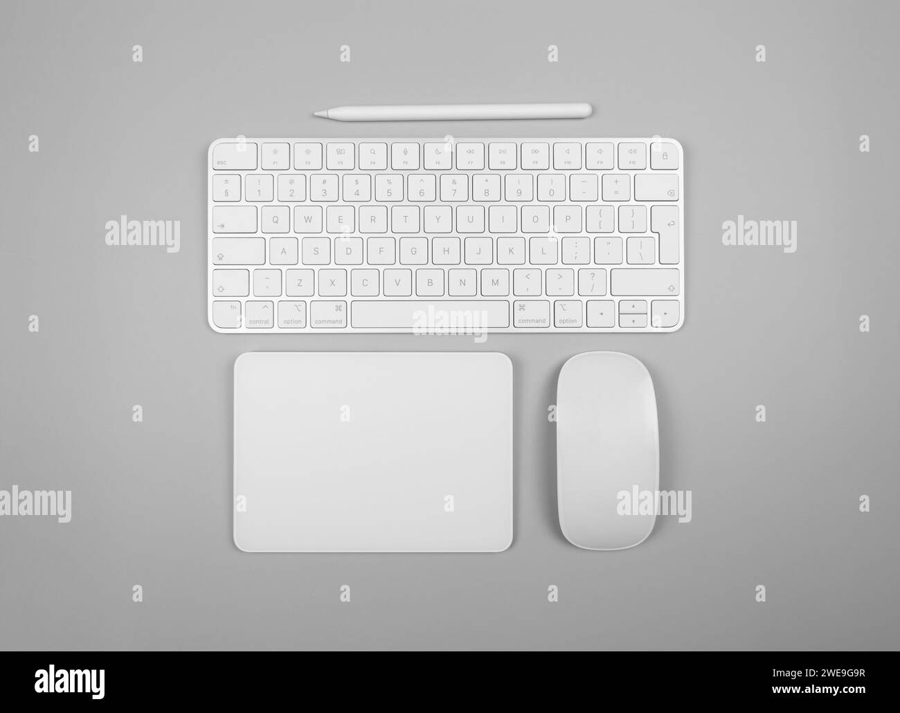 Top view of white keyboard, touchpad, mouse and pen on light grey background. Modern office flat lay, copy space. Stock Photo