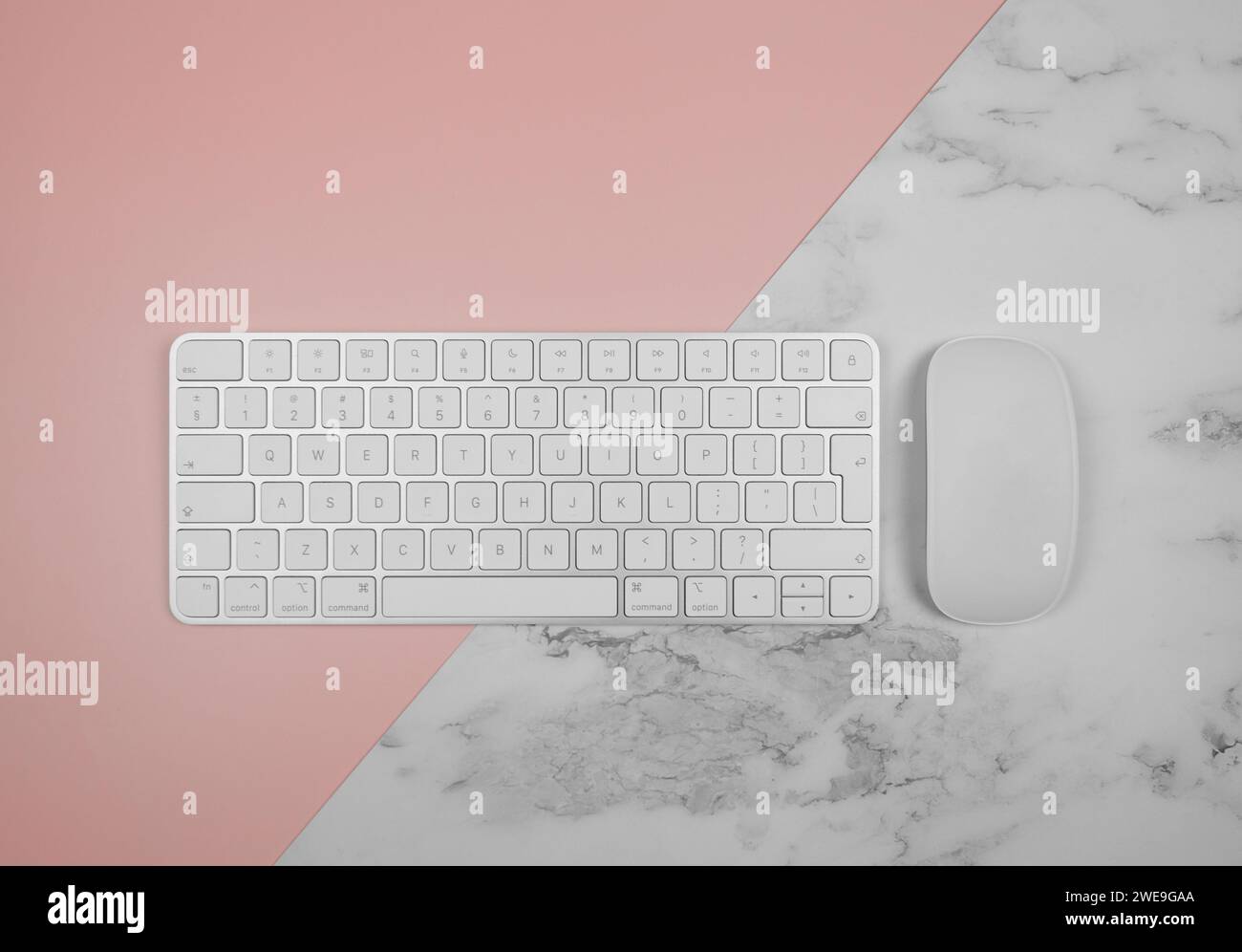 Top view of white keyboard, mouse on pink and white marble background. Modern office flat lay, copy space. Stock Photo