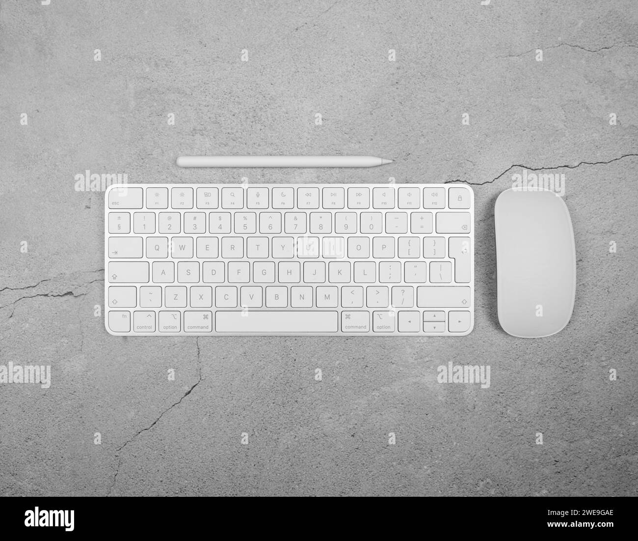 Top view of white keyboard, mouse and pen on concrete background. Modern office flat lay, copy space. Stock Photo