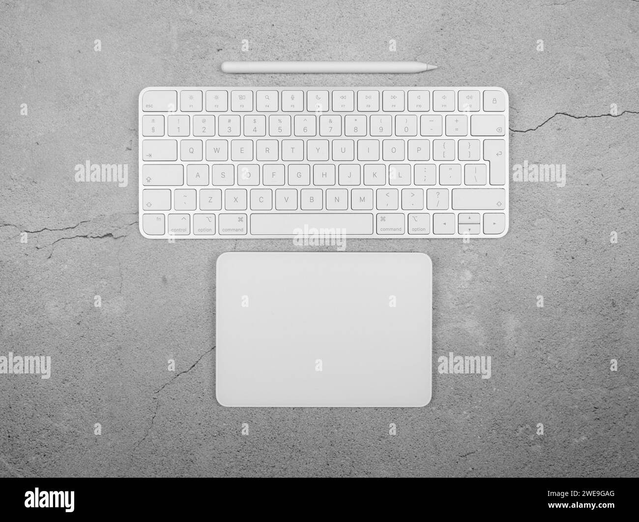 Top view of white keyboard, touchpad and pen on concrete background. Modern office flat lay, copy space. Stock Photo