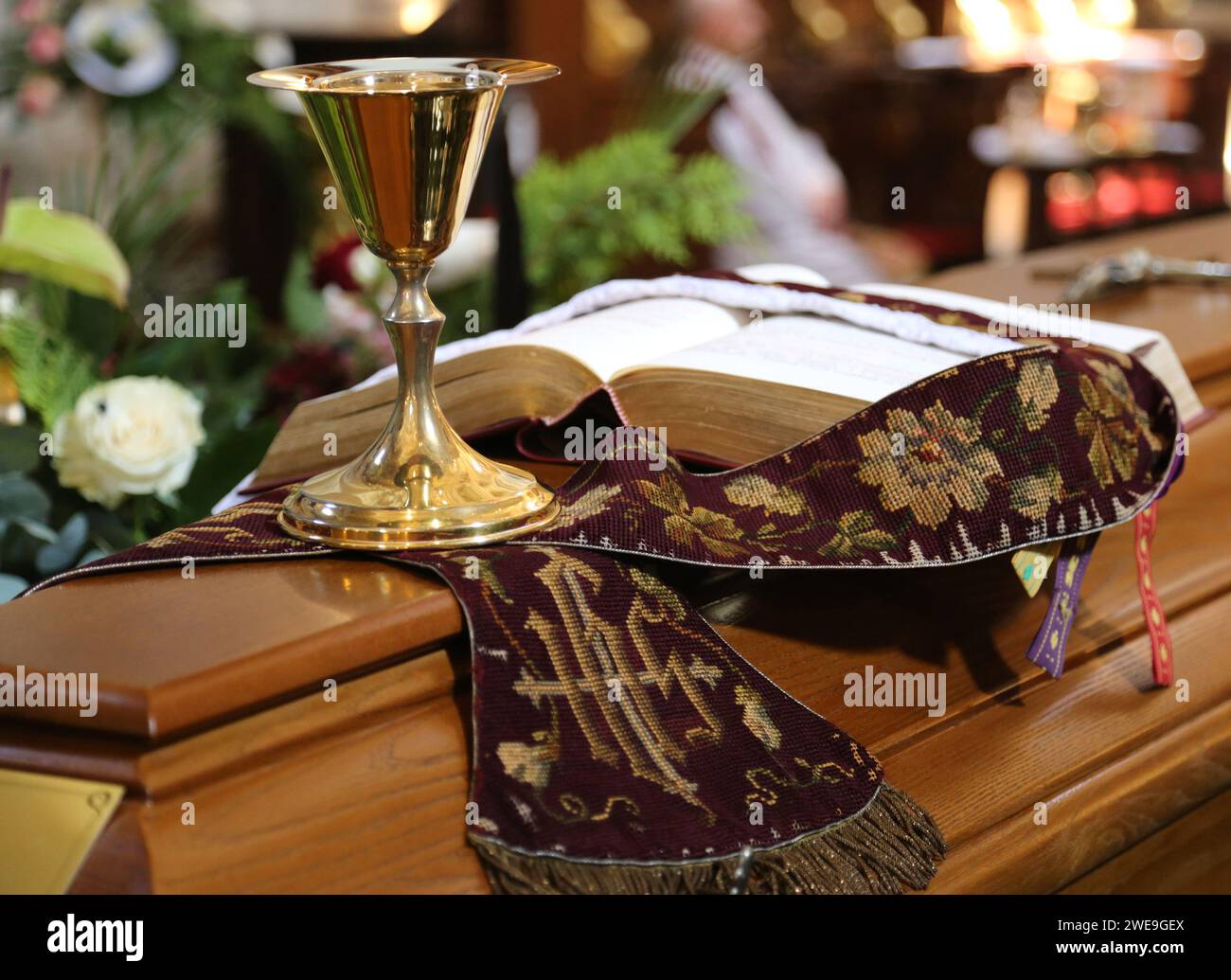 Golden chalice and paten, stole and missal book put on the lid of the coffin during the catholic priest funeral. Stock Photo