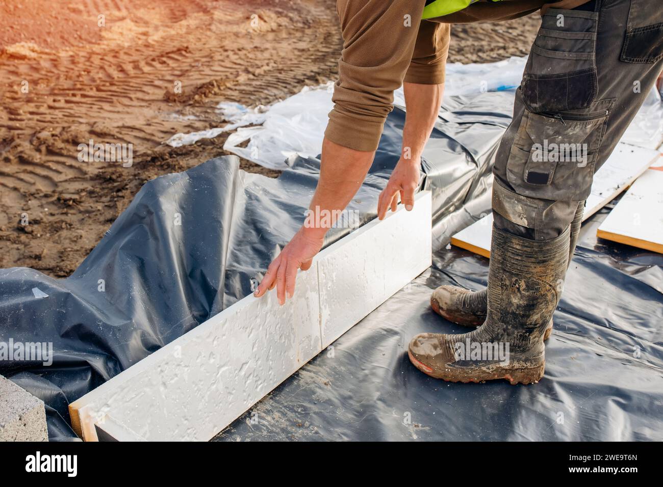 Builder placing polystyrene insulation boards on waterproofing membrane
