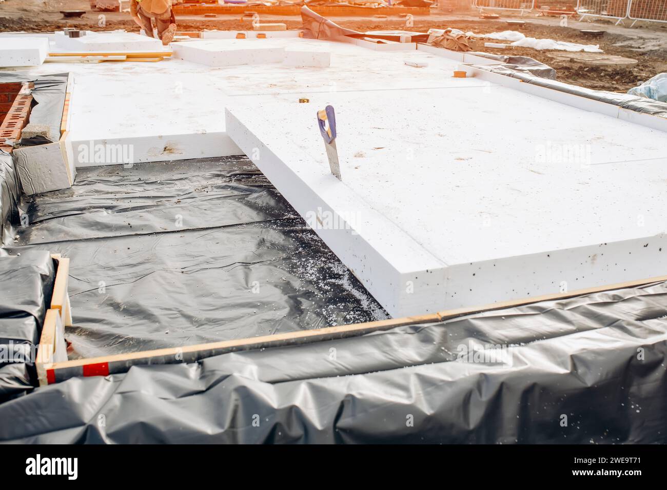 Builder placing polystyrene insulation boards on waterproofing membrane