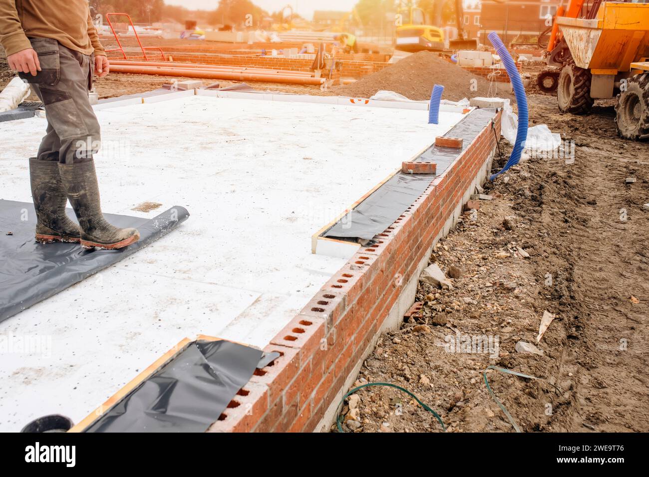 Builder placing polystyrene insulation boards on waterproofing membrane