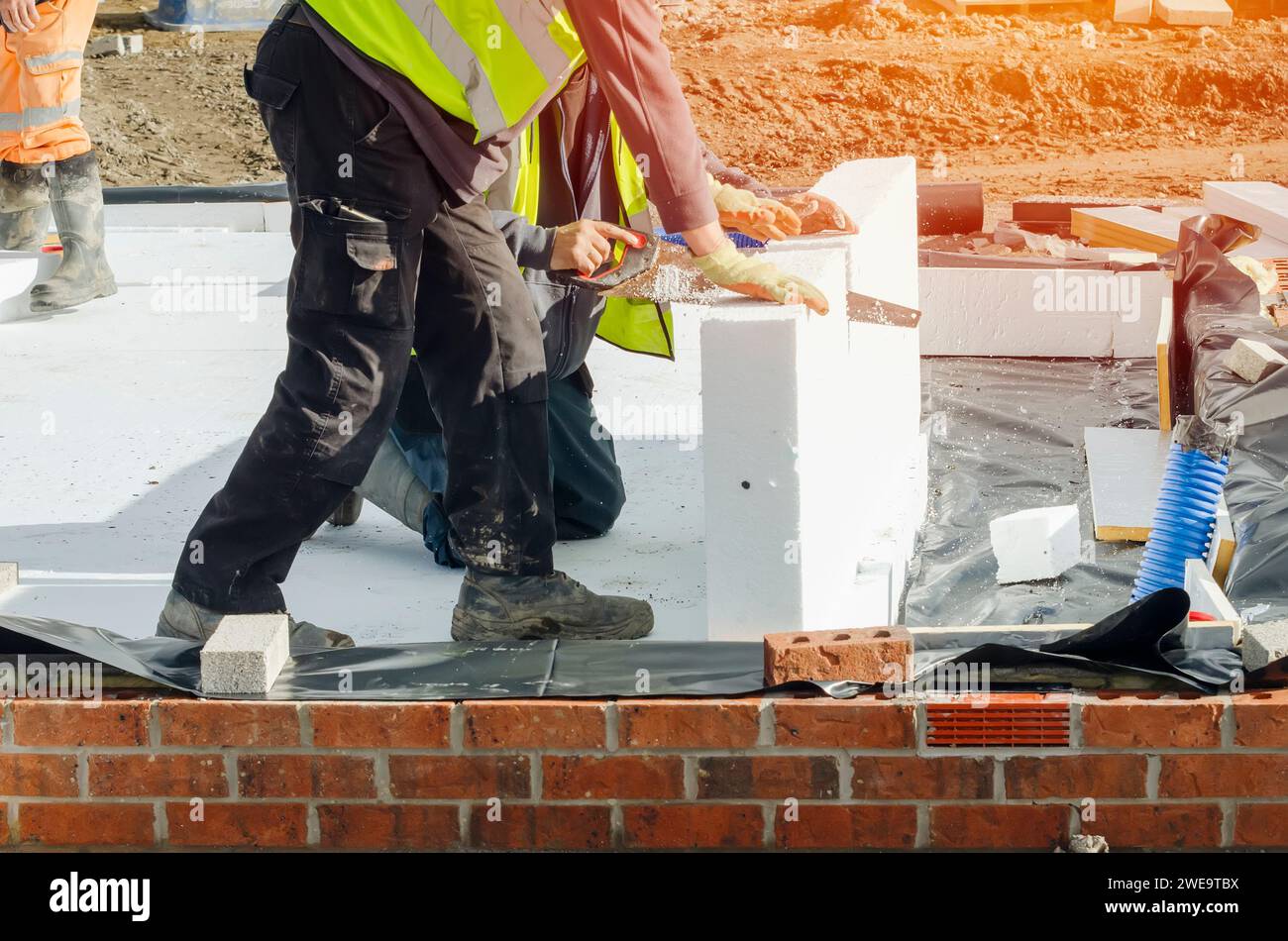 Builder placing polystyrene insulation boards on waterproofing membrane