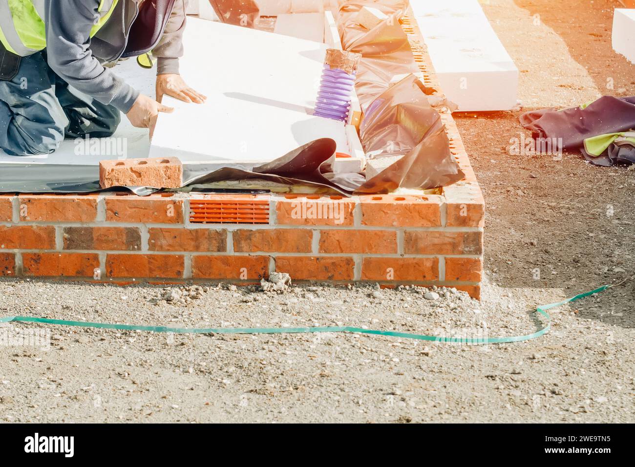 Builder placing polystyrene insulation boards on waterproofing membrane