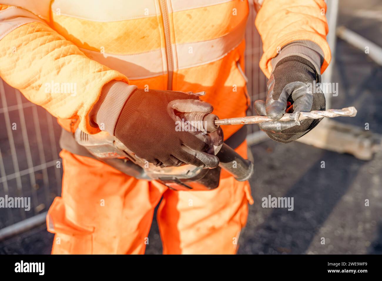 Closeup of a builder fitting drill bit into a cordless hammer drill to