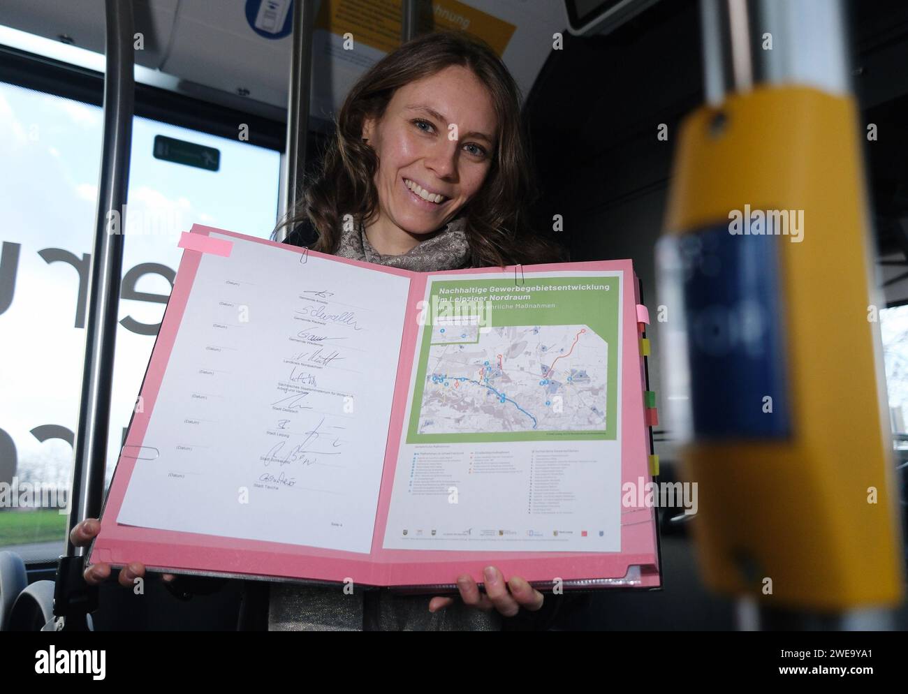 Leipzig, Germany. 24th Jan, 2024. Kerstin Löbel, project developer for local transport concepts, holds a map and a list of signatures from local politicians on an e-bus. The occasion is the presentation of the planned transport development in Leipzig's northern region. Credit: Sebastian Willnow/dpa/Alamy Live News Stock Photo