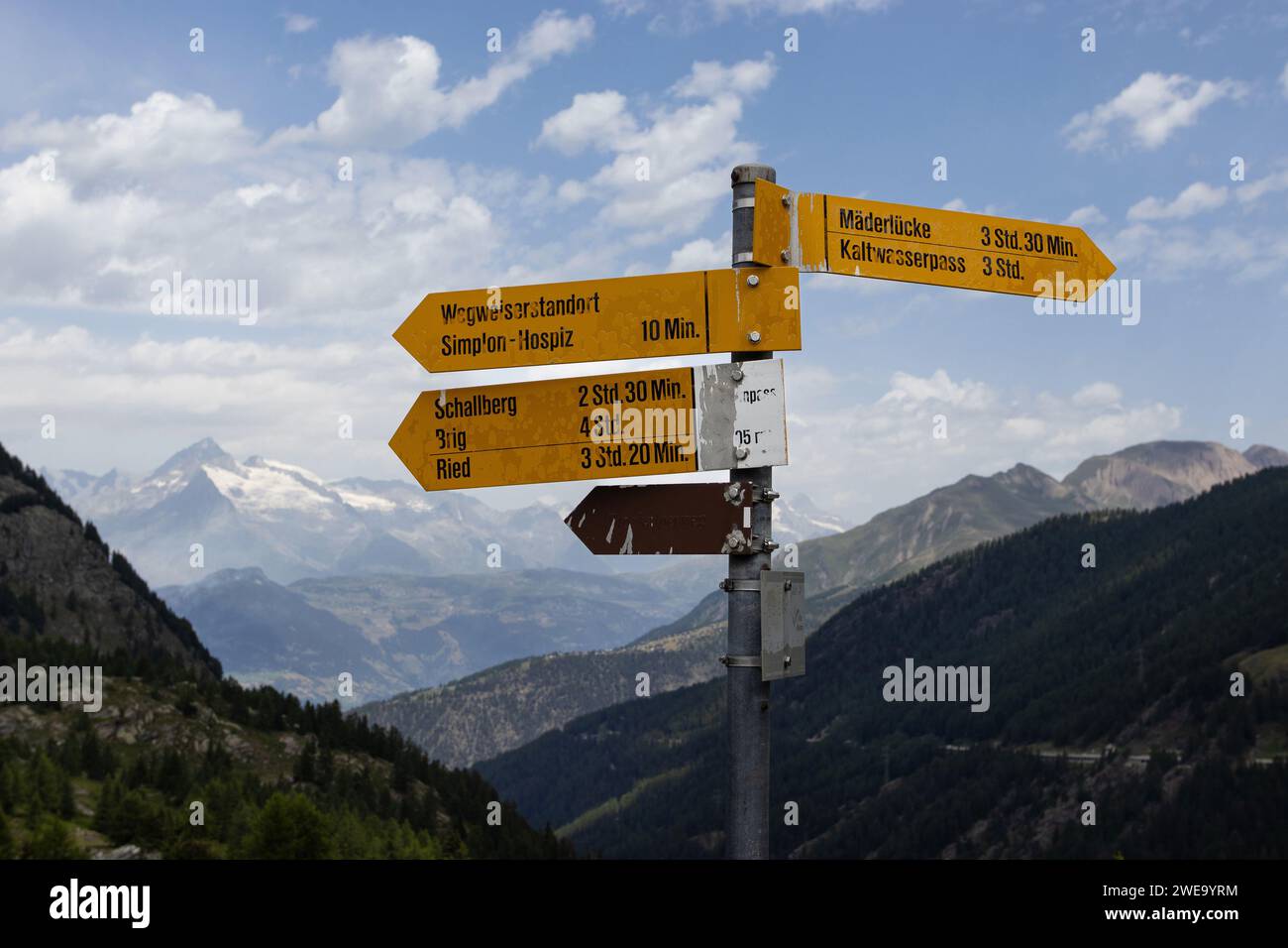 Walking trail directional signs at the famous Simplon Pass in Switzerland, with distance information and a background of mountains. Copy space above l Stock Photo