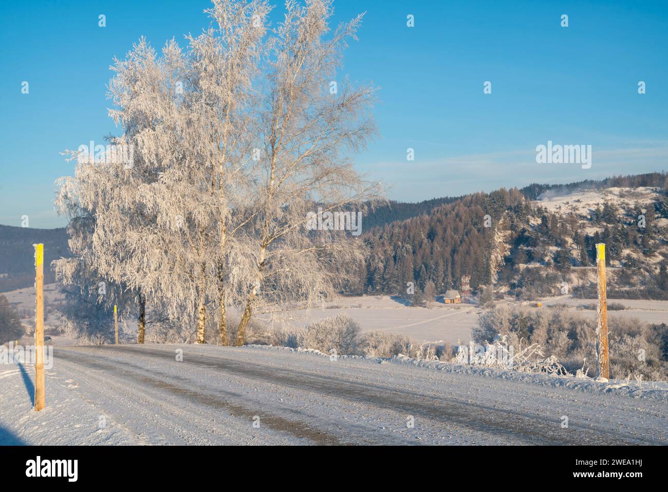 Mountain road on an extremely cold morning, surface covered with ice and snow. Stock Photo