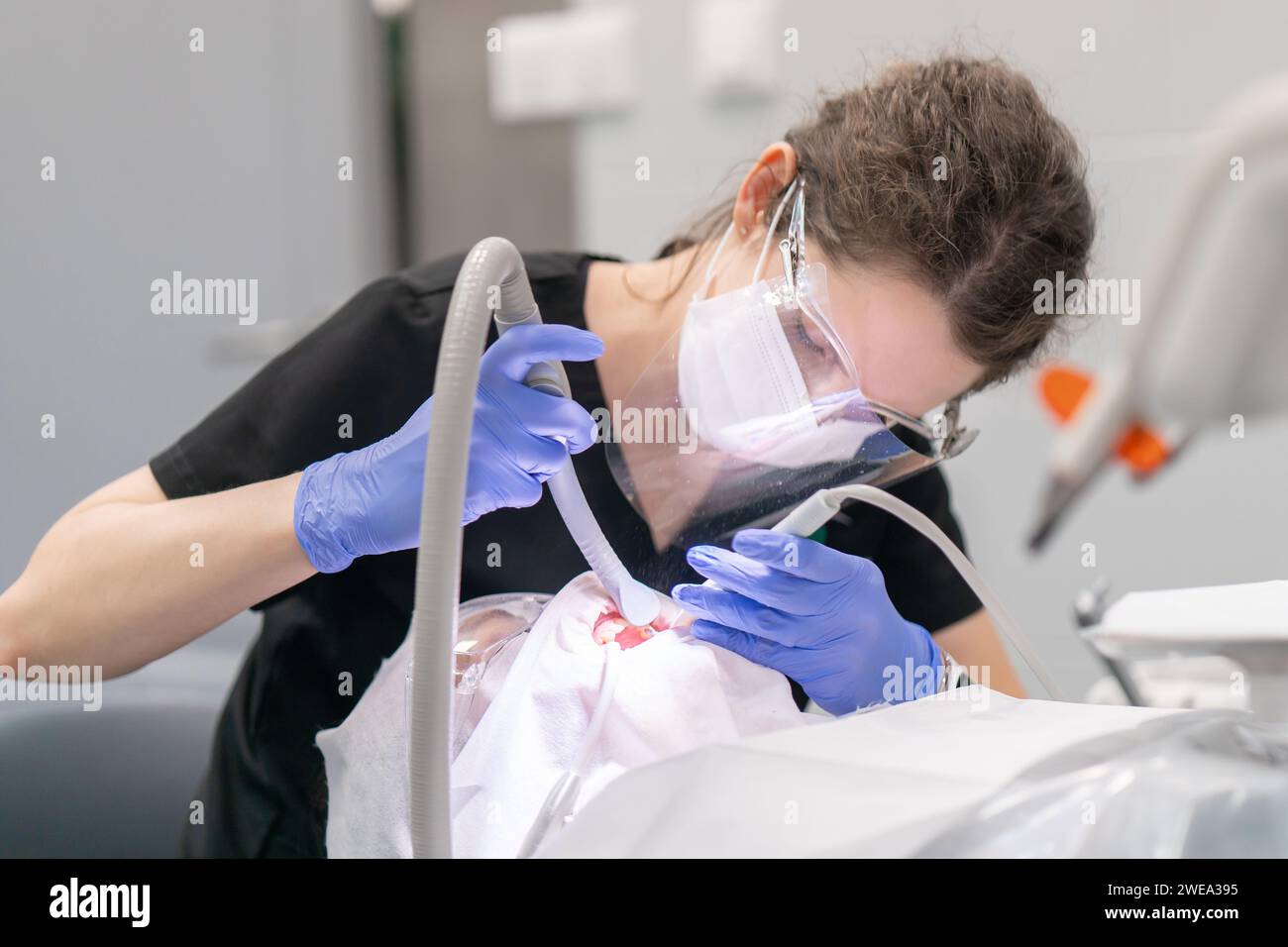 A female dentist performs a dental procedure for a patient, cleaning