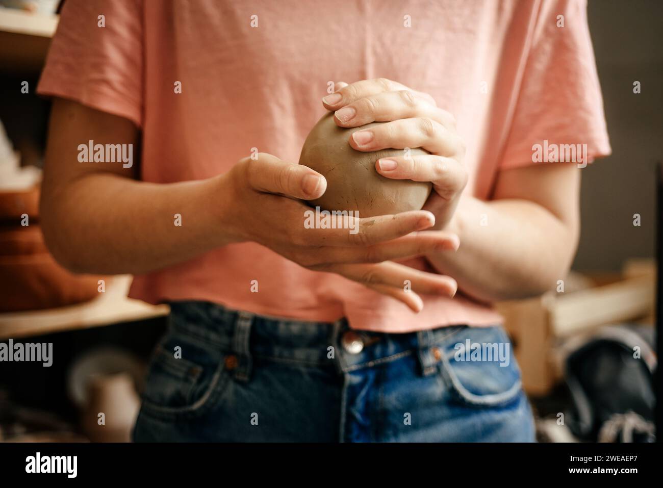 A round lump of raw white clay in the hands of a ceramist Stock Photo