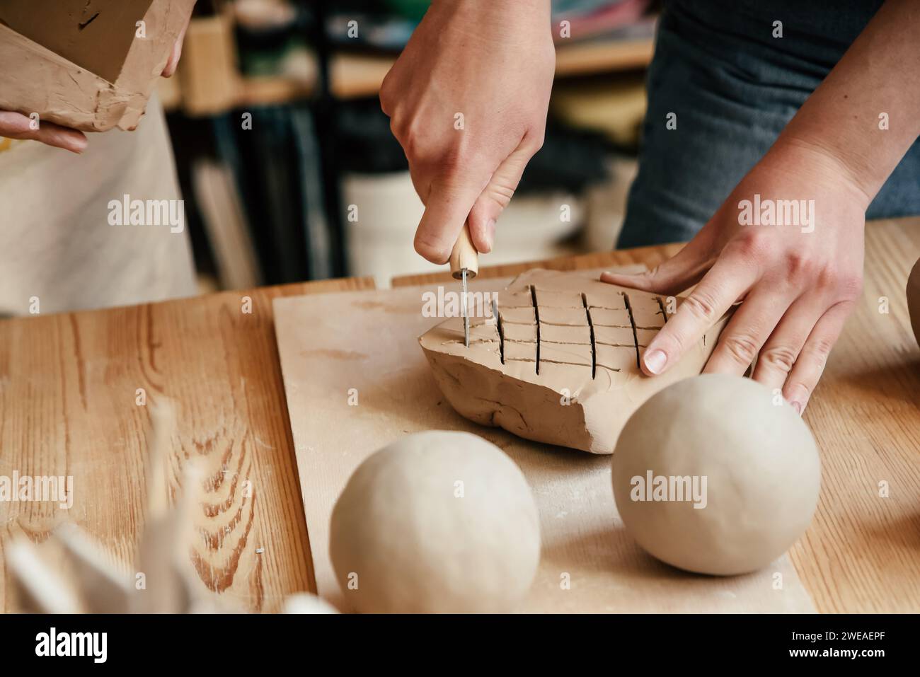 Potter cuts piece of clay with knife to soften it. Stock Photo