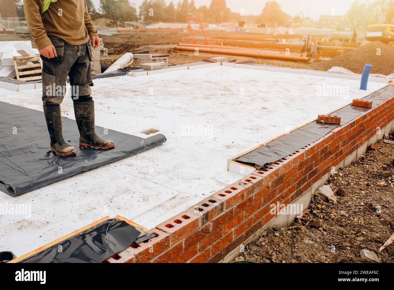 Builder placing polystyrene insulation boards on waterproofing membrane
