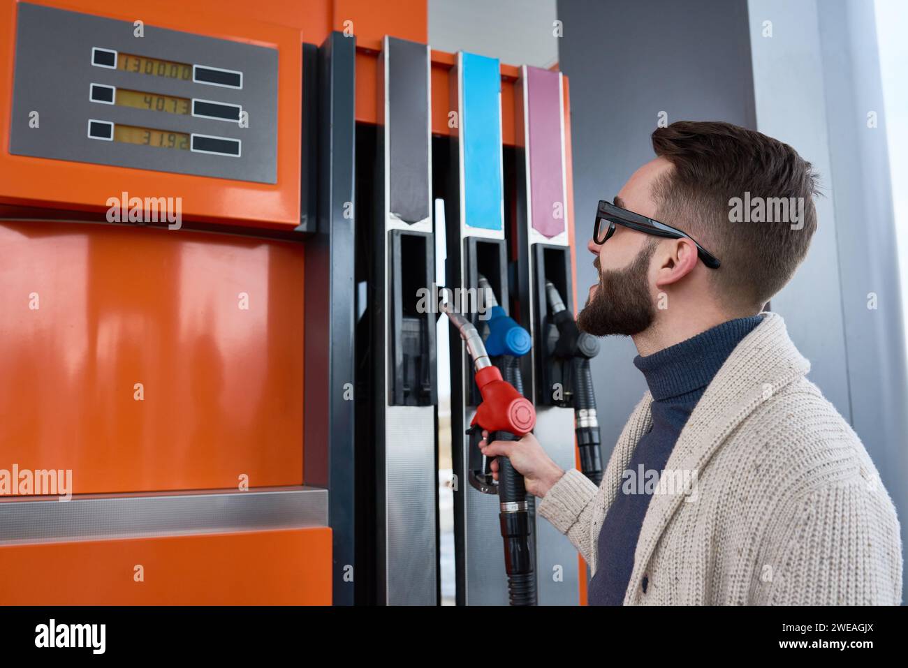 Side view of modern young man dressed in casual clothes at gas station ...