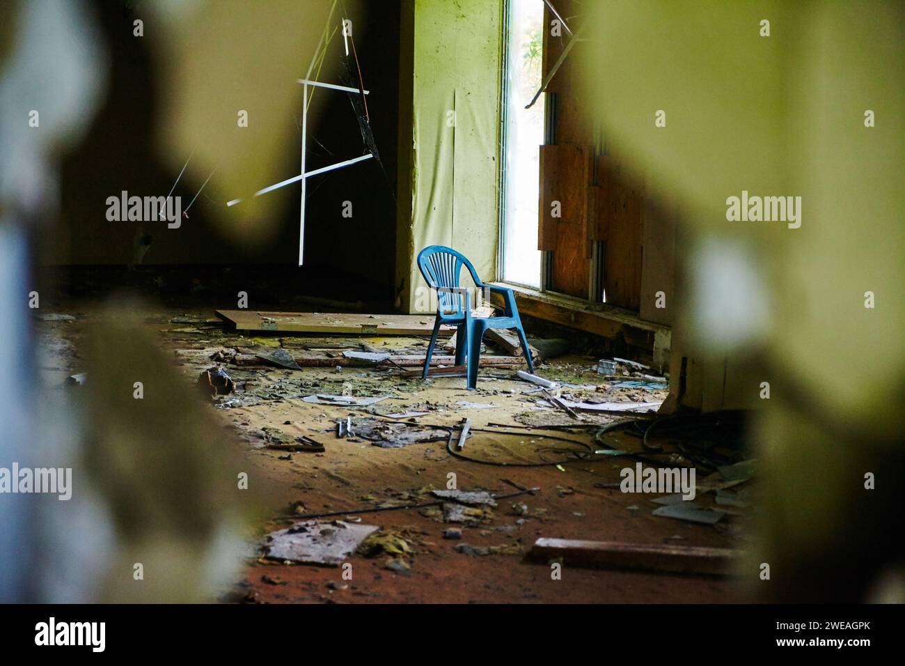 Blue Chair in Derelict Hotel Interior, Peeking Through Decay Stock Photo