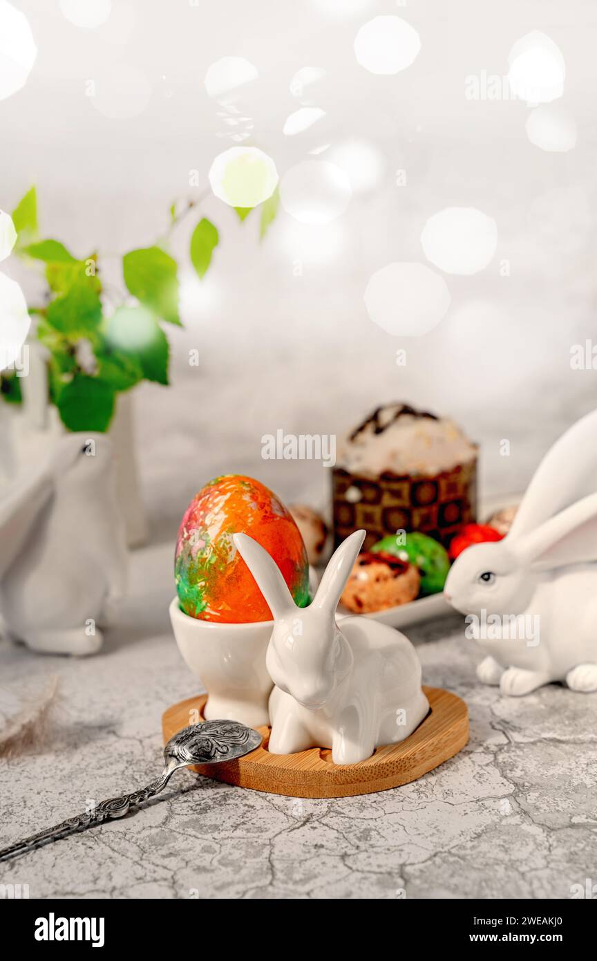 Happy Easter, Easter painted egg in the shape of a bunny shaped egg cup on the table. Stylish holiday table decor. Naturally dyed Easter eggs and spri Stock Photo