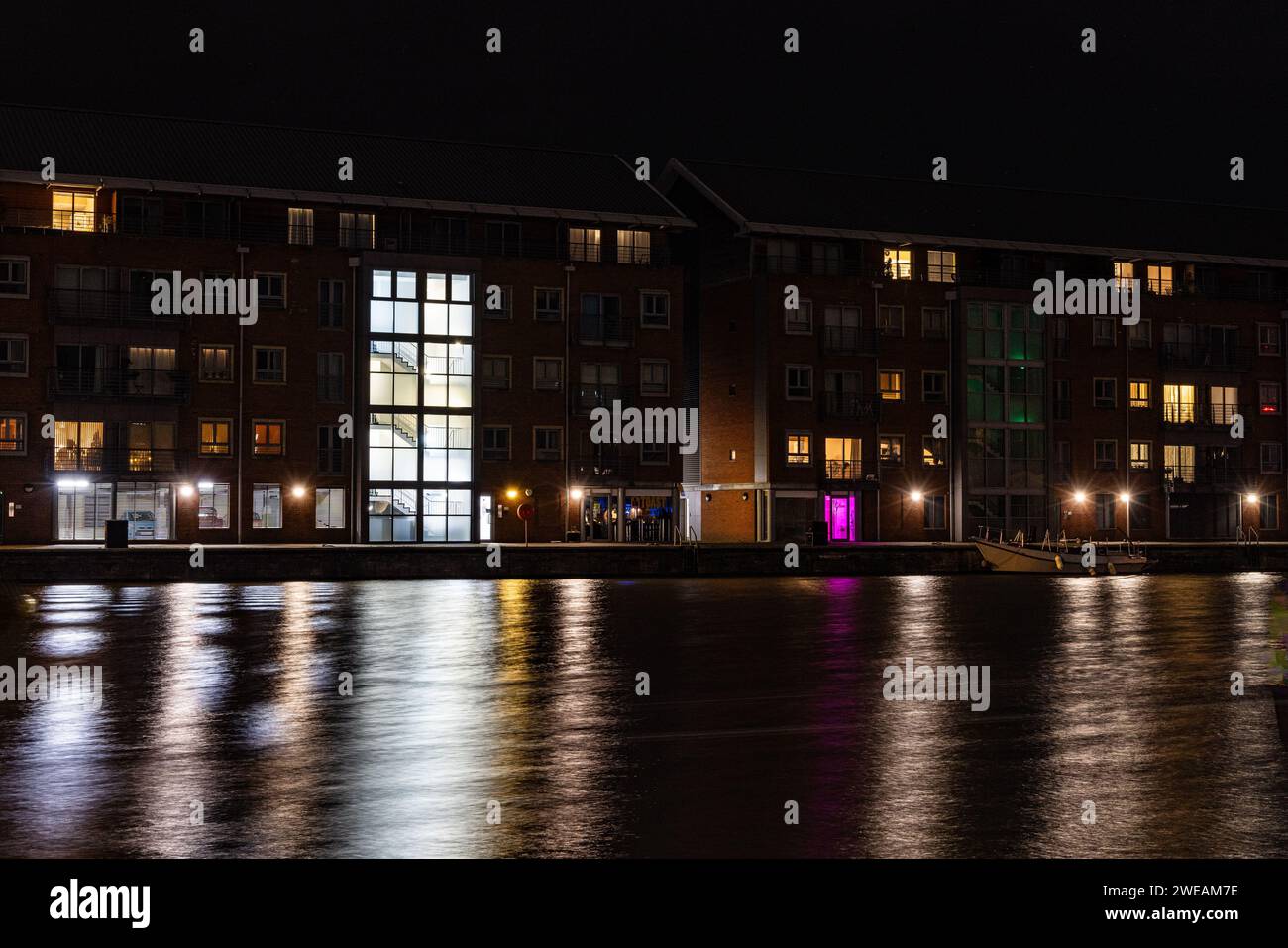 Illuminated quayside apartments across the quay at the historic docks at Gloucester at night in