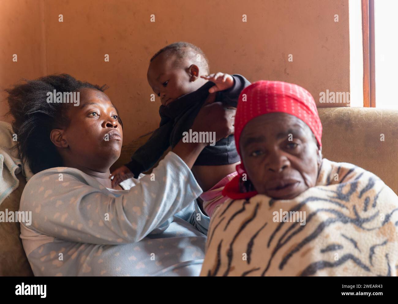 african refugee destitute family  bonding  together in the corner of a room, poverty, inside the house Stock Photo