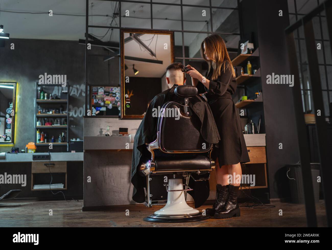 Beautiful Young female barber making men's hairstyle using Haircut