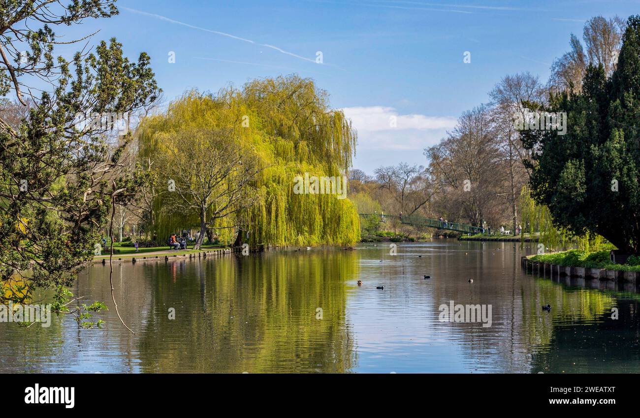 Beddington Park Wallington Surrey UK showing the lake with people in the background enjoying the sunshine spring 2023 Stock Photo