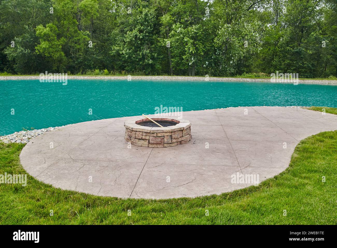 Serene Waterfront Fire Pit Patio with Lush Greenery Stock Photo