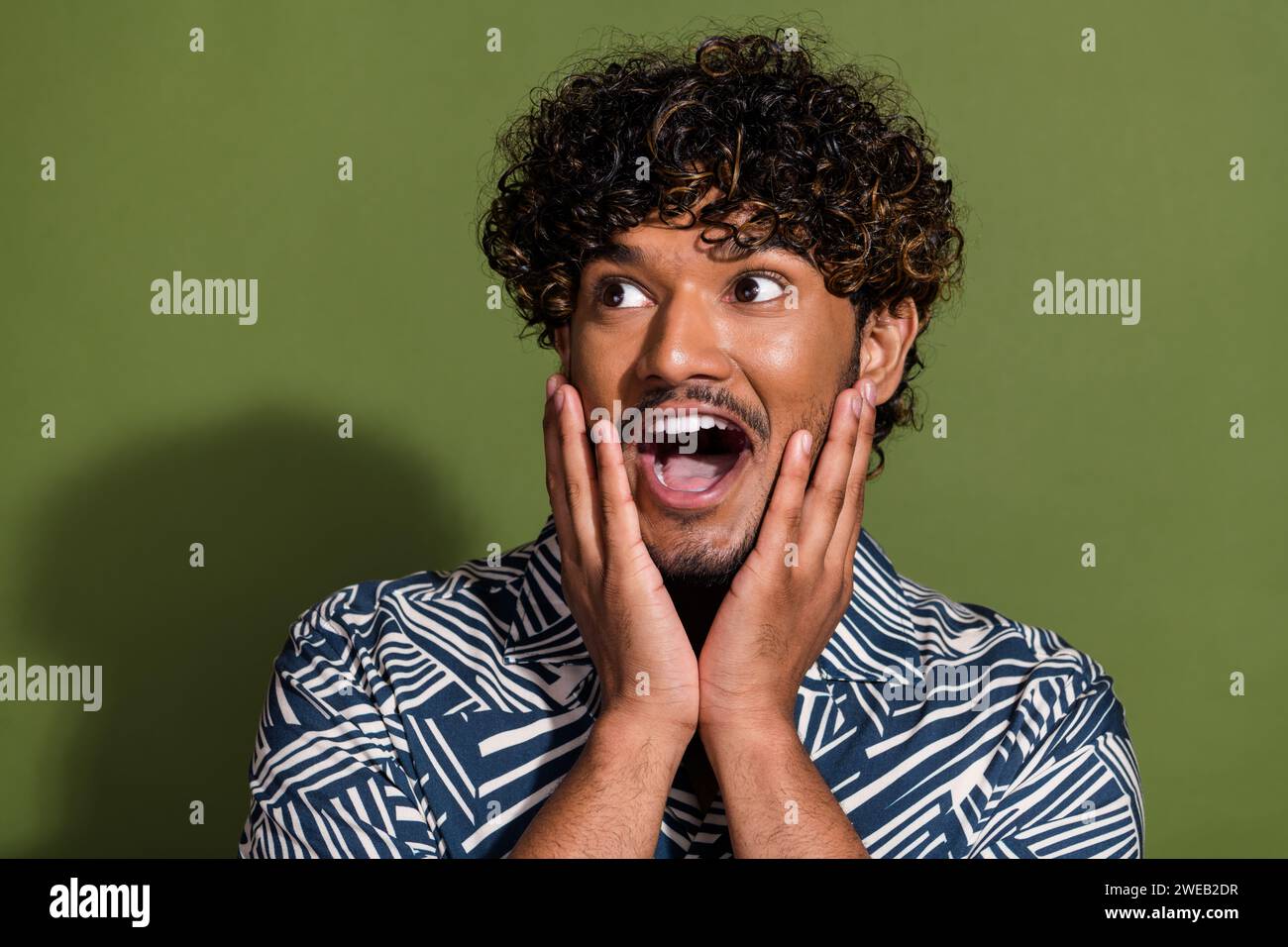 Portrait of funky young funny guy touching cheeks looking left side ...