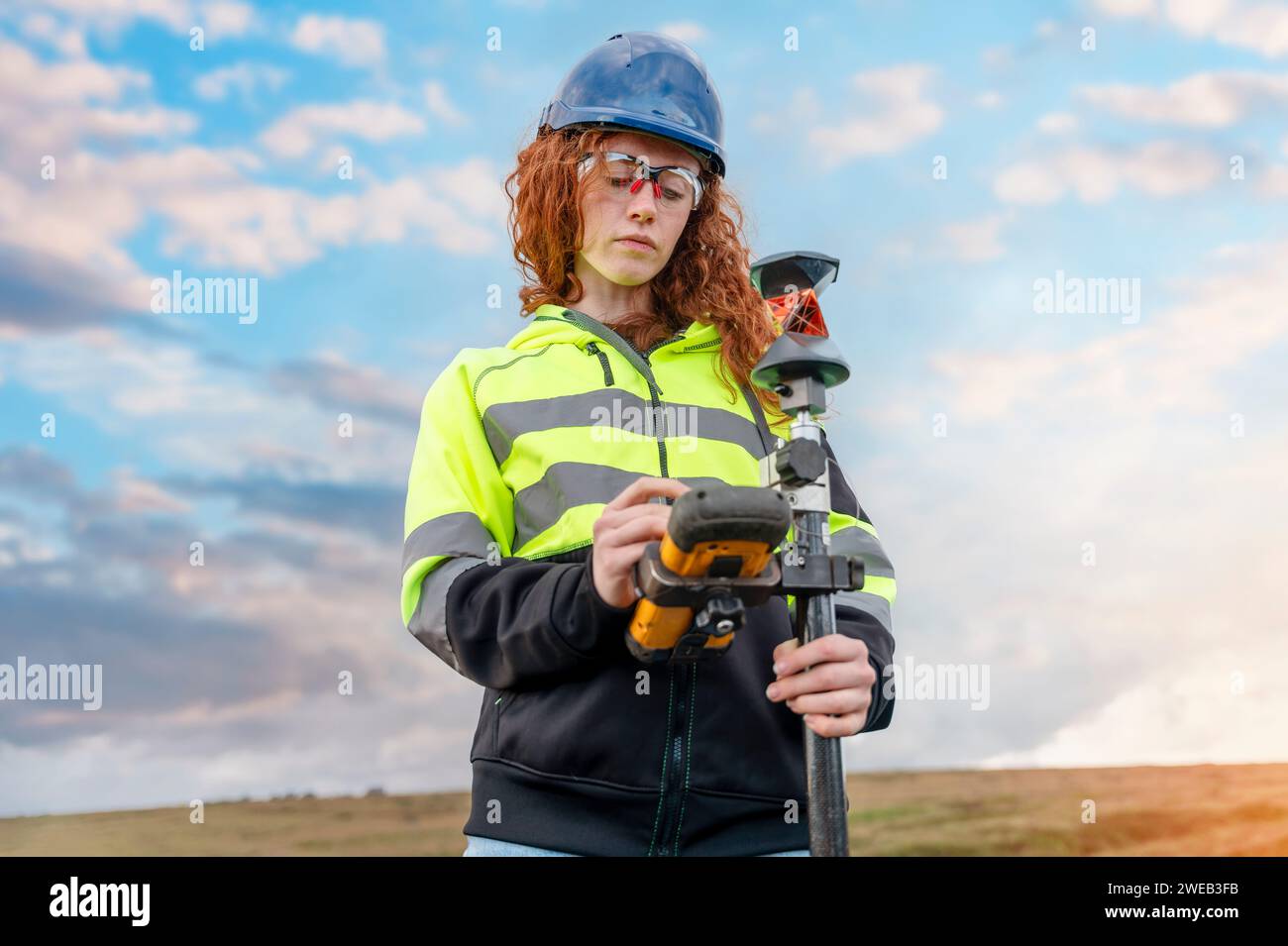 Female Woman land surveyor working with moder surveying geodesic instrument tachometer checking coordinates of land for development. Young pretty woma Stock Photo