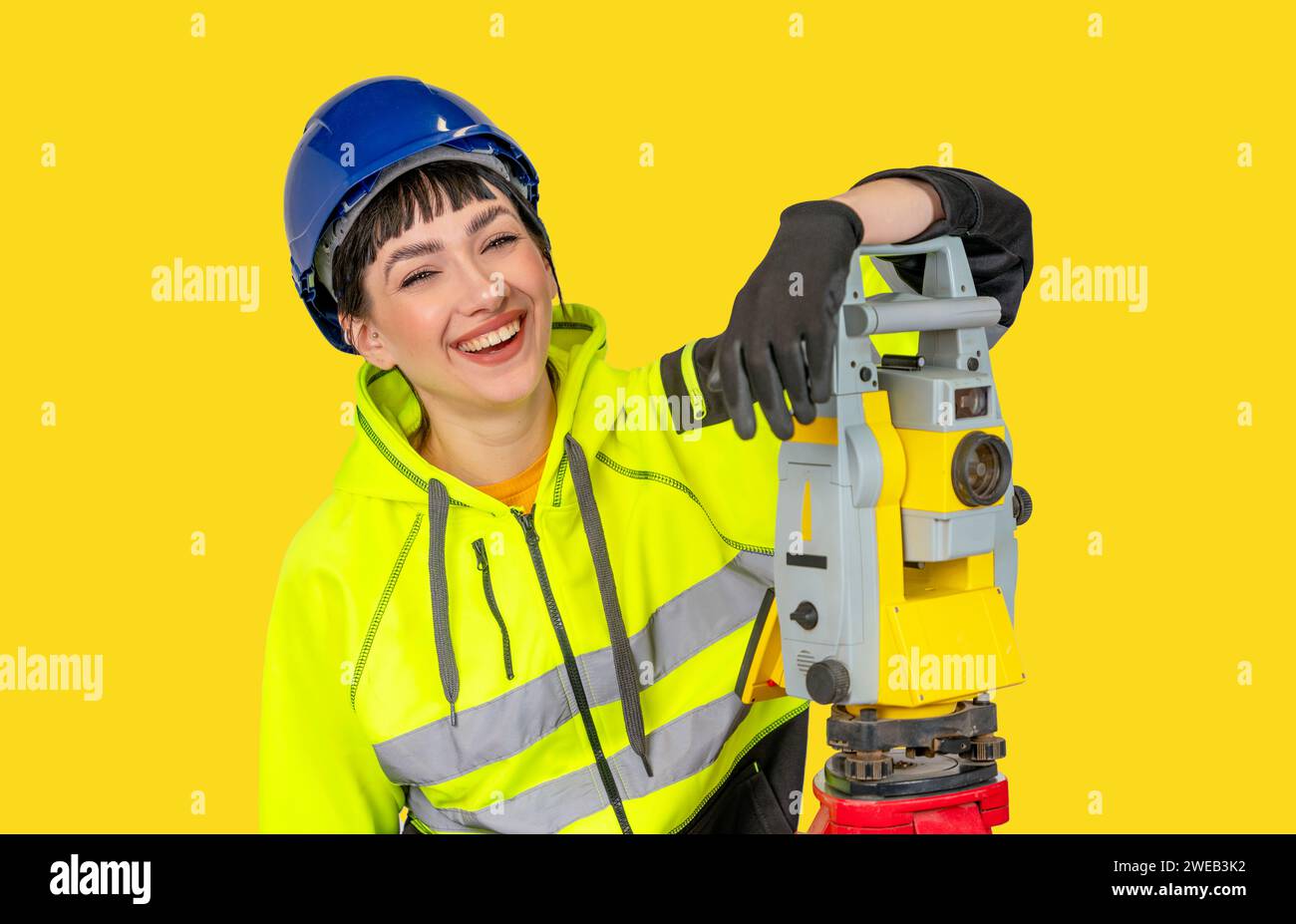 Smiling Woman in hard hat and  protective clothes land surveyor working with modern surveying geodesic instrument tachometer checking coordinates. You Stock Photo