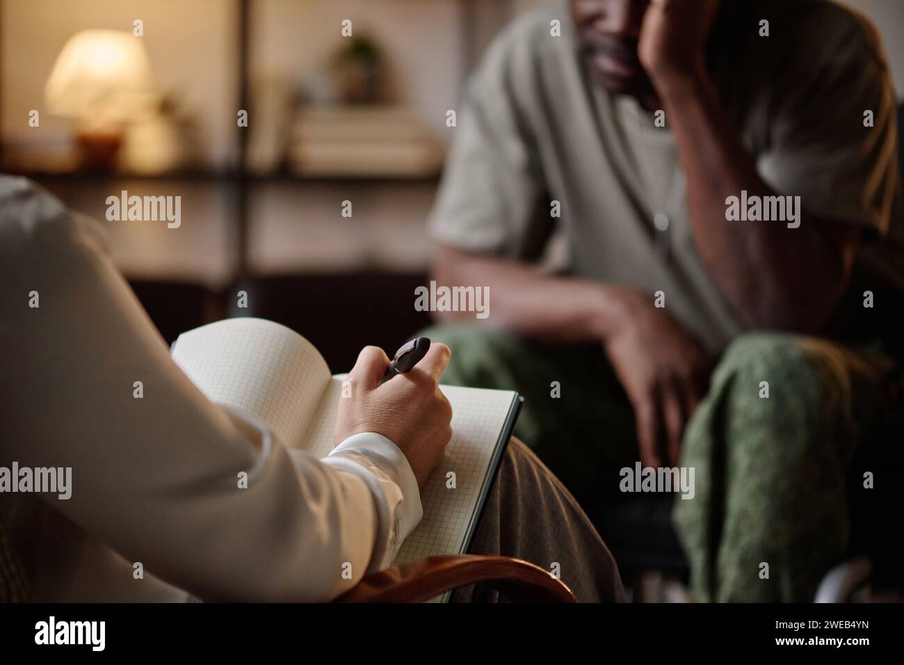 Psychologist taking notes while black war veteran having conversation with her at private session Stock Photo