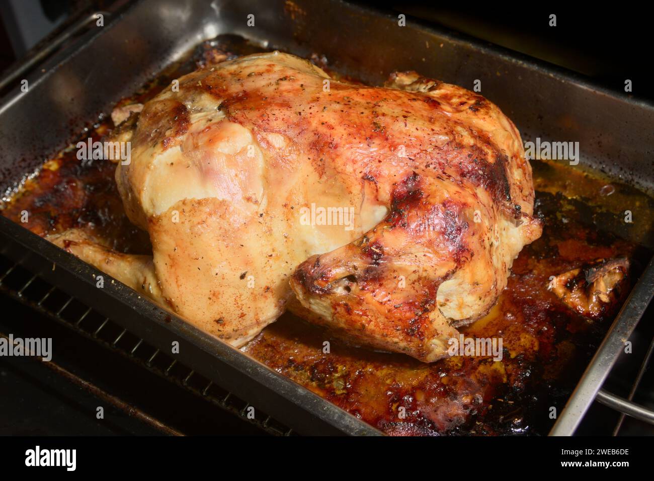 Close-up of a whole chicken that has been roasted in a home oven tray, resulting in crispy, golden skin ready to taste Stock Photo