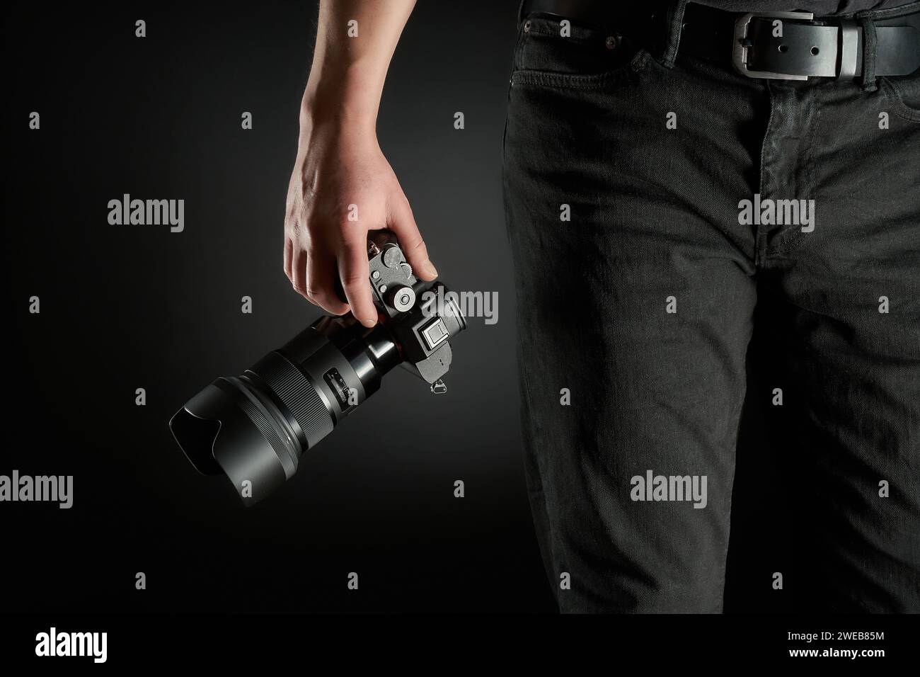 young photographer holding a mirrorless camera in his hand studio shot Stock Photo