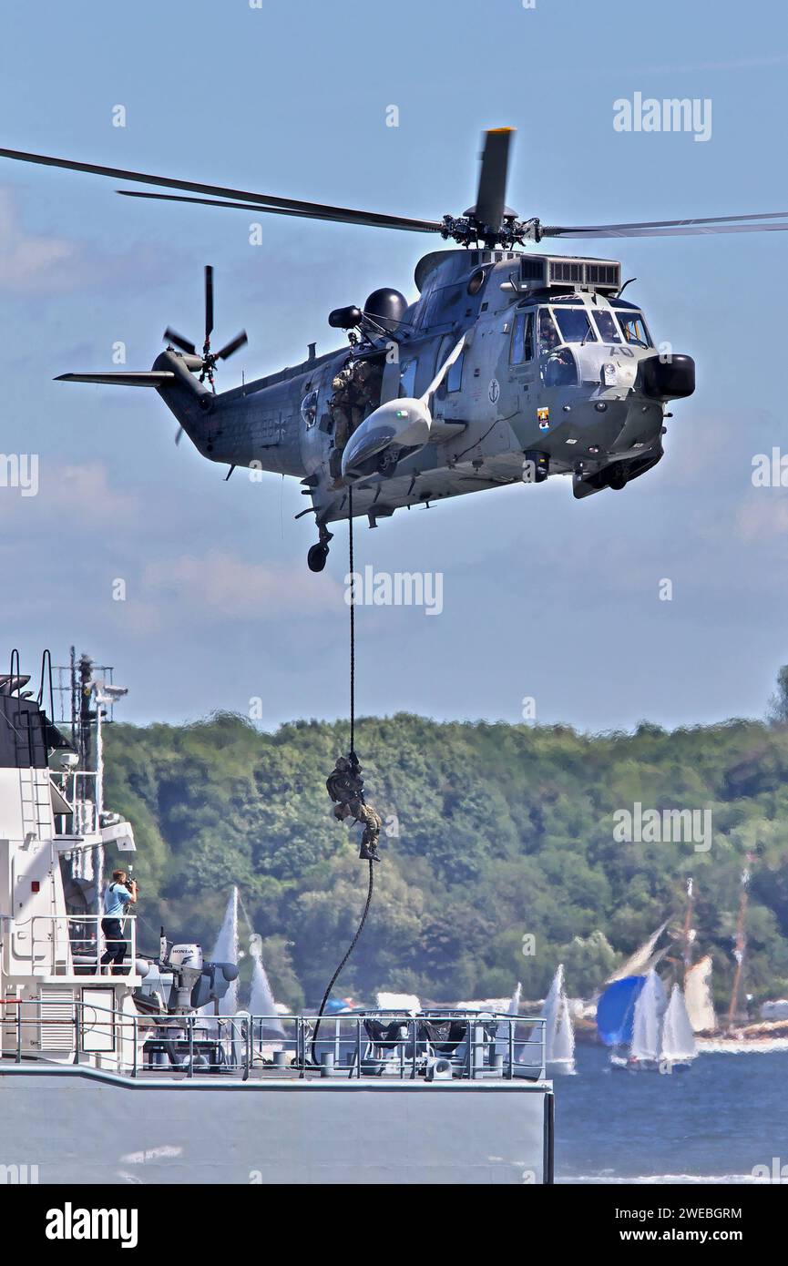 Ein Mehrzweckhubschrauber Mk41 Sea King der Marine. Kampfschwimmer beim Fast Roping auf ein Boot. Die Kampfschwimmer seilen sich auf ein Marineboot ab. Hochkant. Ein Mehrzweckhubschrauber Mk41 Sea King der Marine. Kampfschwimmer beim Fast Roping auf ein Boot. Die Kampfschwimmer seilen sich auf ein Marineboot ab. Hochkant. *** A naval Mk41 Sea King multi-purpose helicopter Combat swimmers fast roping onto a boat The combat swimmers abseiling onto a naval boat Upright A naval Mk41 Sea King multi-purpose helicopter Combat swimmers fast roping onto a boat The combat swimmers abseiling onto a naval Stock Photo