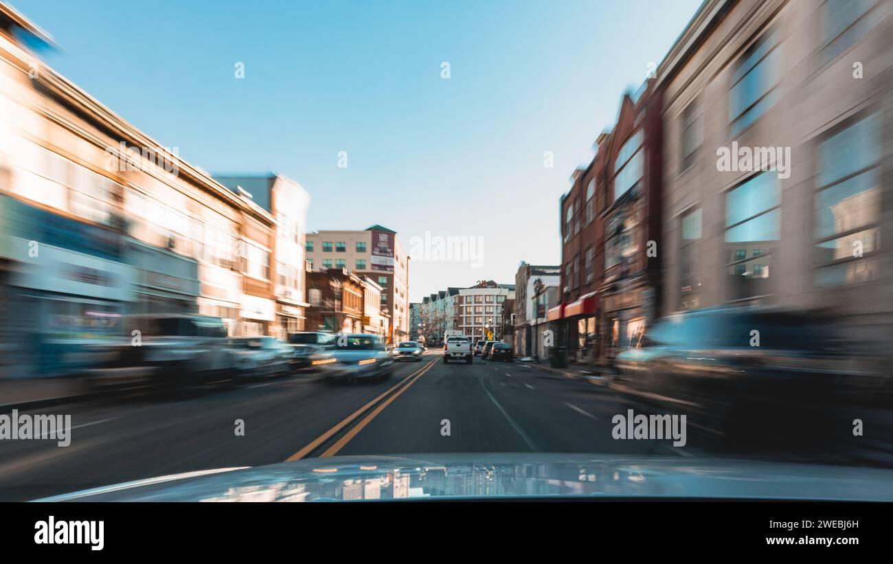 Car driving down a sunny city street with motion blur Stock Photo