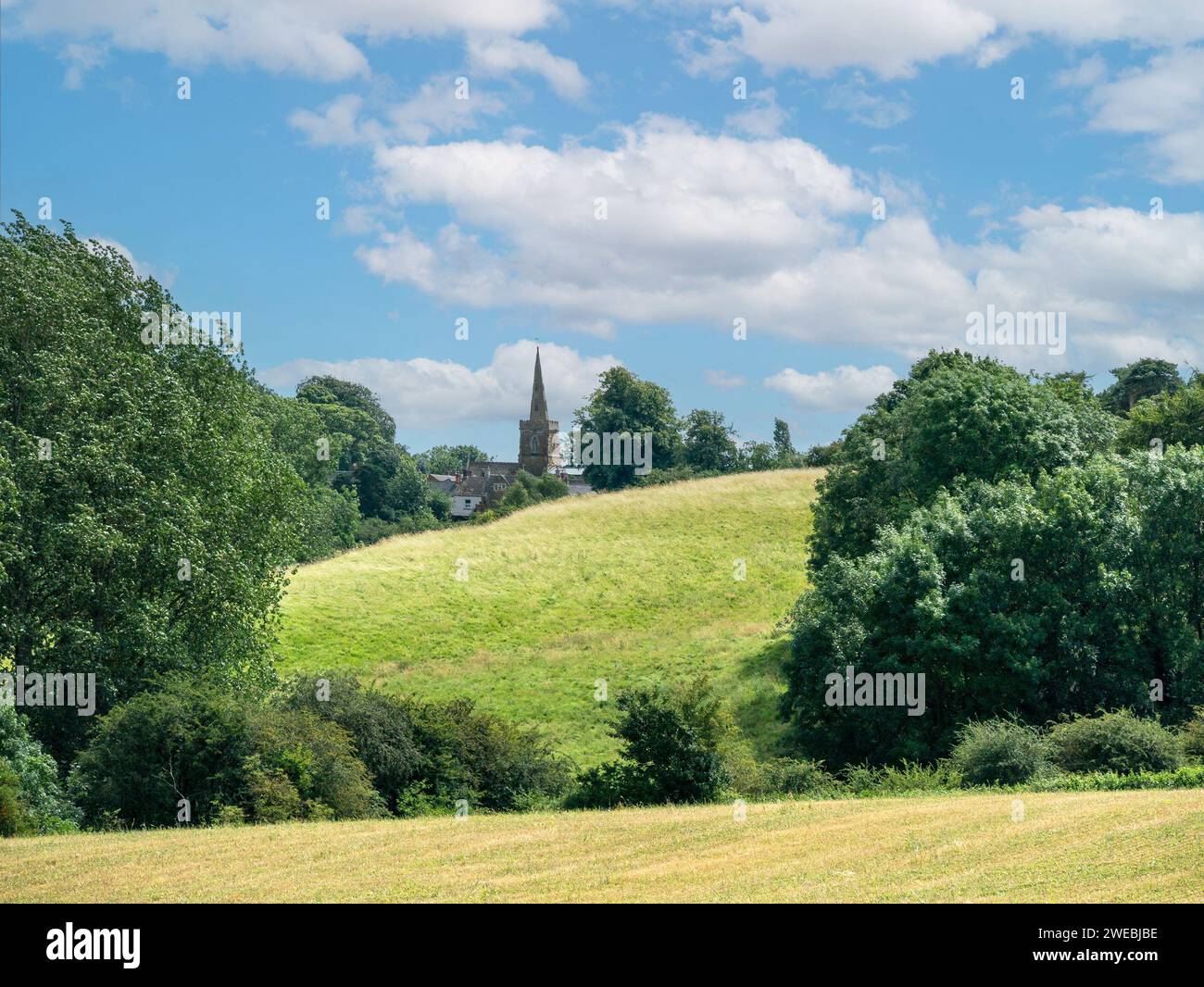 Pretty old houses and tower of Somerby Parish church as seen in the distance across farm fields, Somerby, Leicestershire, England, UK Stock Photo