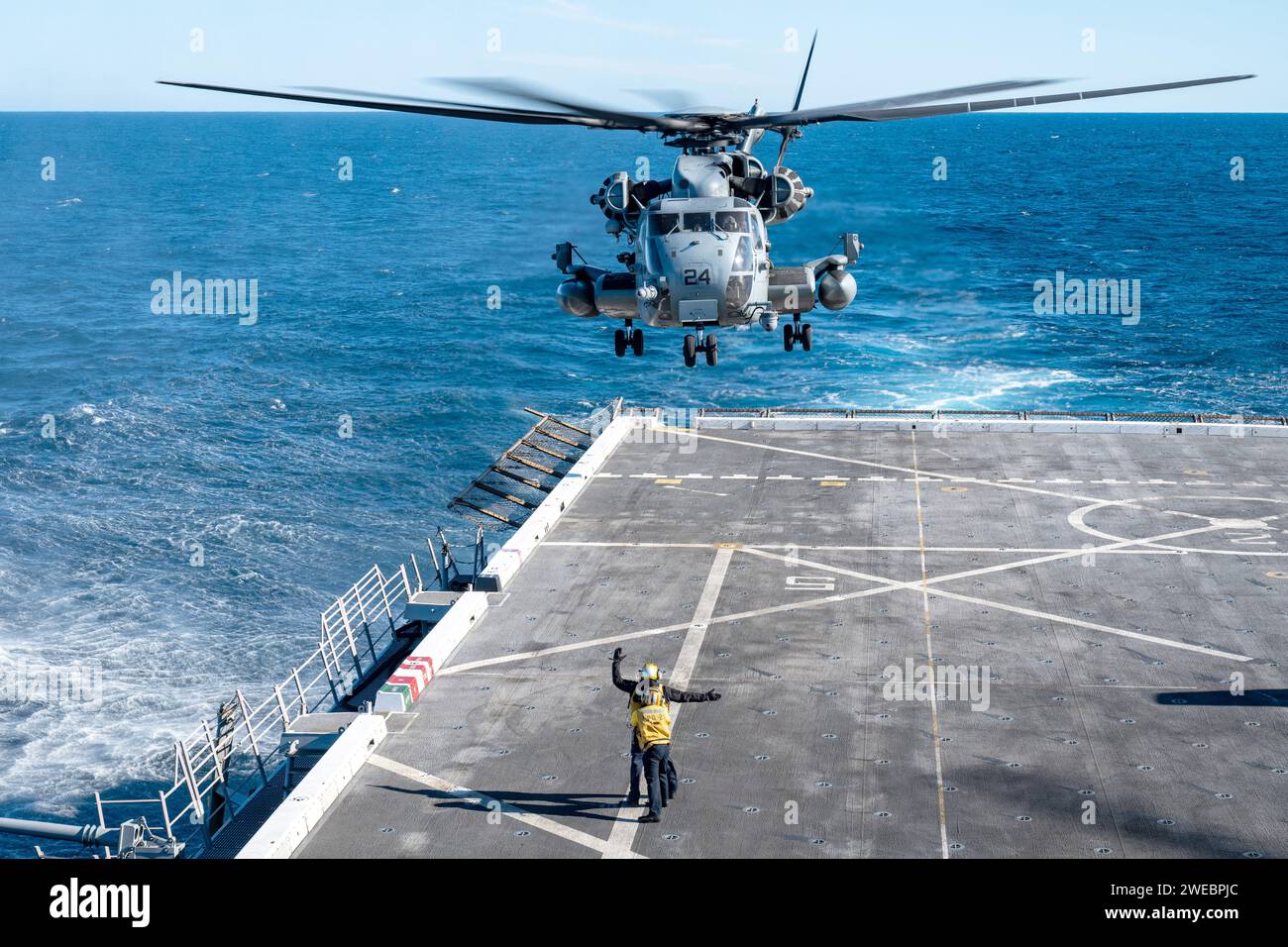 Aviation Boatswain supports Aviation Boatswain's Mate as he signals a CH-53E Super Stallion helicopter assigned to the “White Knights” of Marine Medium Tiltrotor Squadron (VMM) 165 (Reinforced) during flight quarters aboard the San Antonio-class amphibious transport dock ship USS Somerset (LPD 25) while underway in the Pacific Ocean Stock Photo