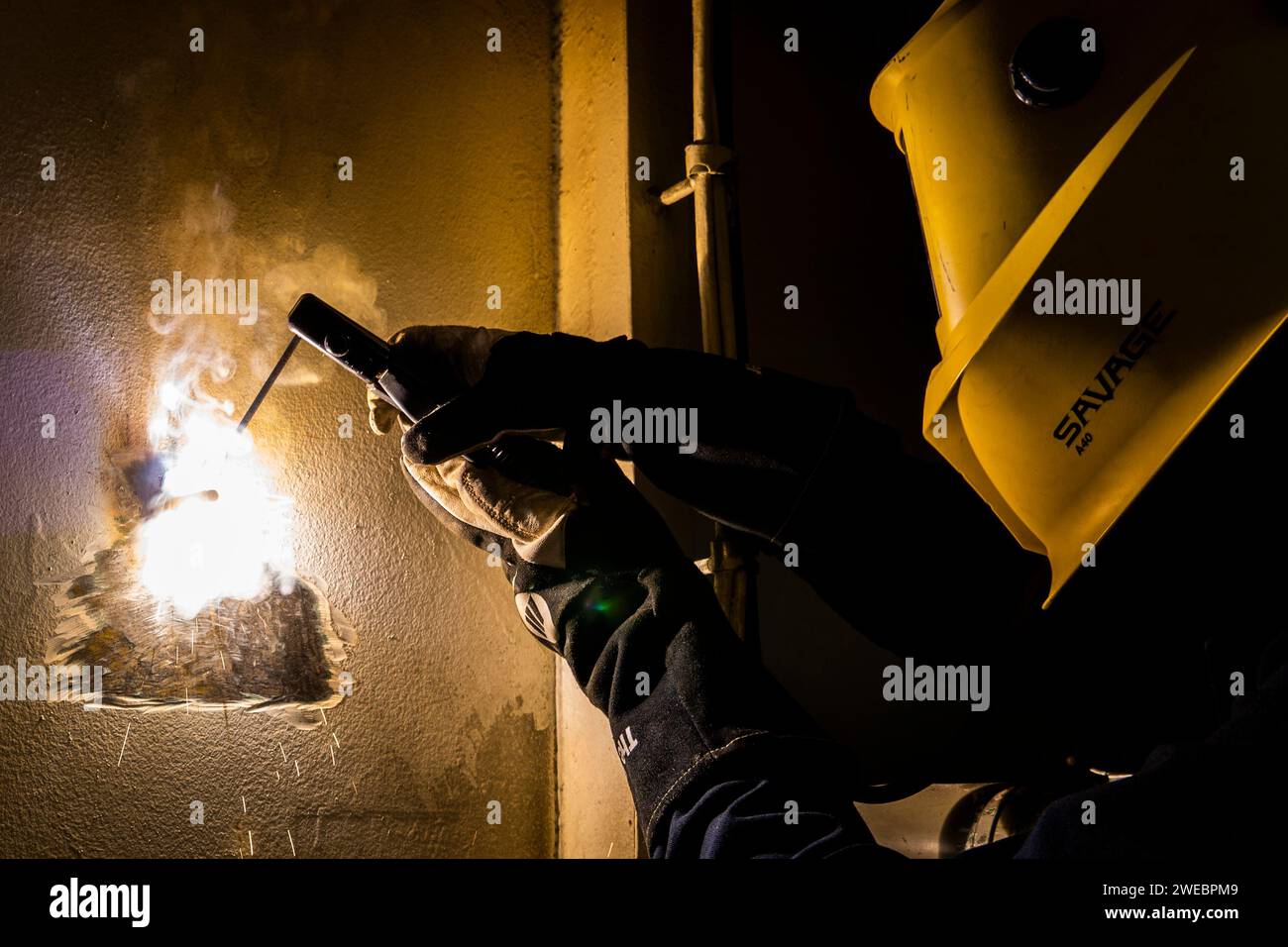 Hull Technician Fireman welds a bolt in the Hull Technician shop aboard USS Boxer (LHD 4) Stock Photo