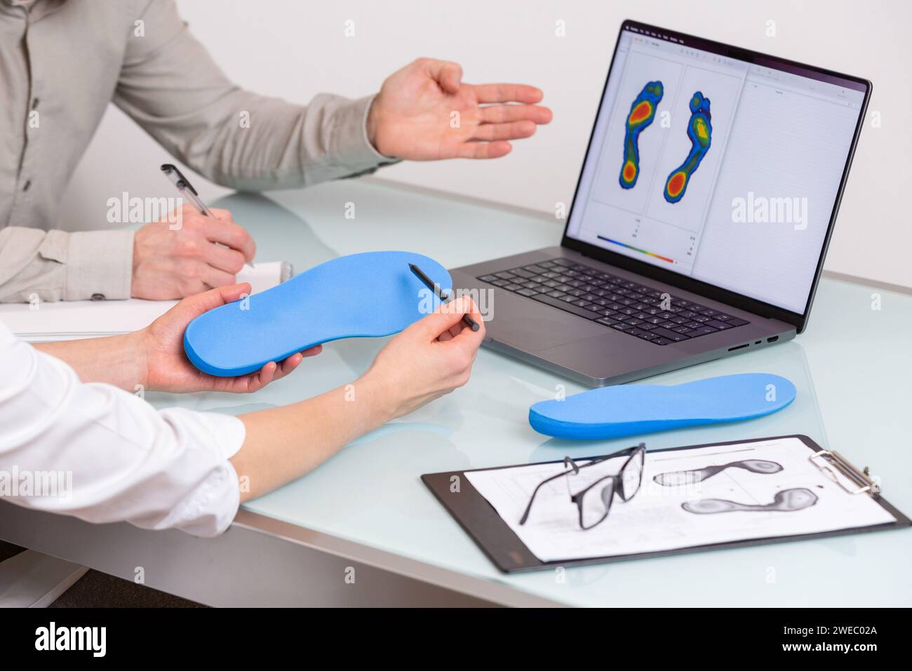 Doctor consulting male patient on custom orthotic insoles in a clinic