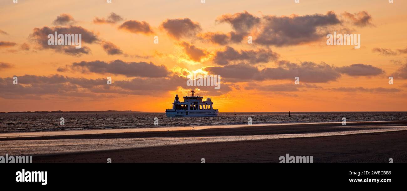Wadden landscape with setting sun and ferry Frisia, Germany, Lower Saxony, Norderney, Norderney Stock Photo