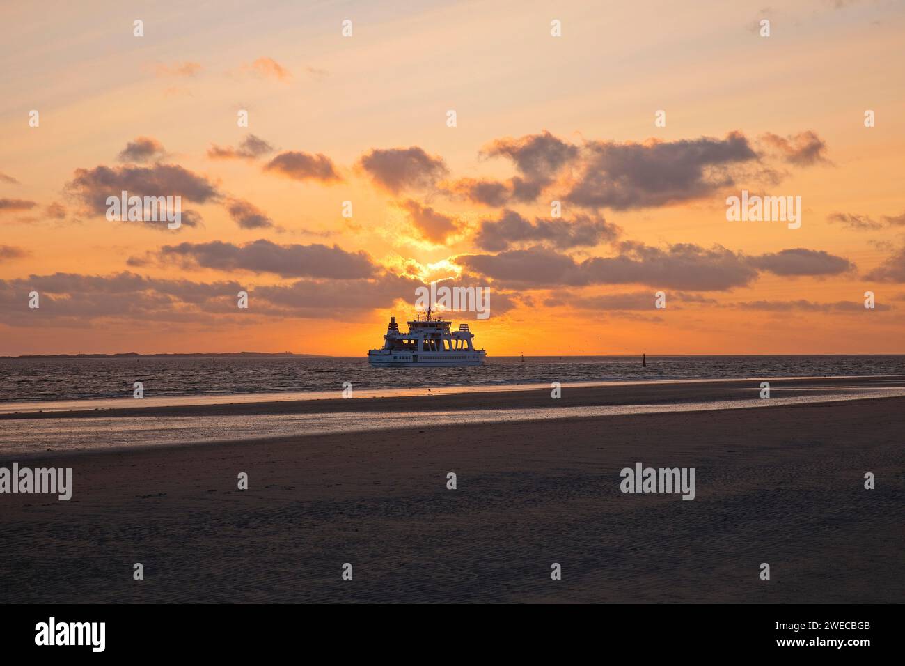 Wadden landscape with setting sun and ferry Frisia, Germany, Lower Saxony, Norderney Stock Photo