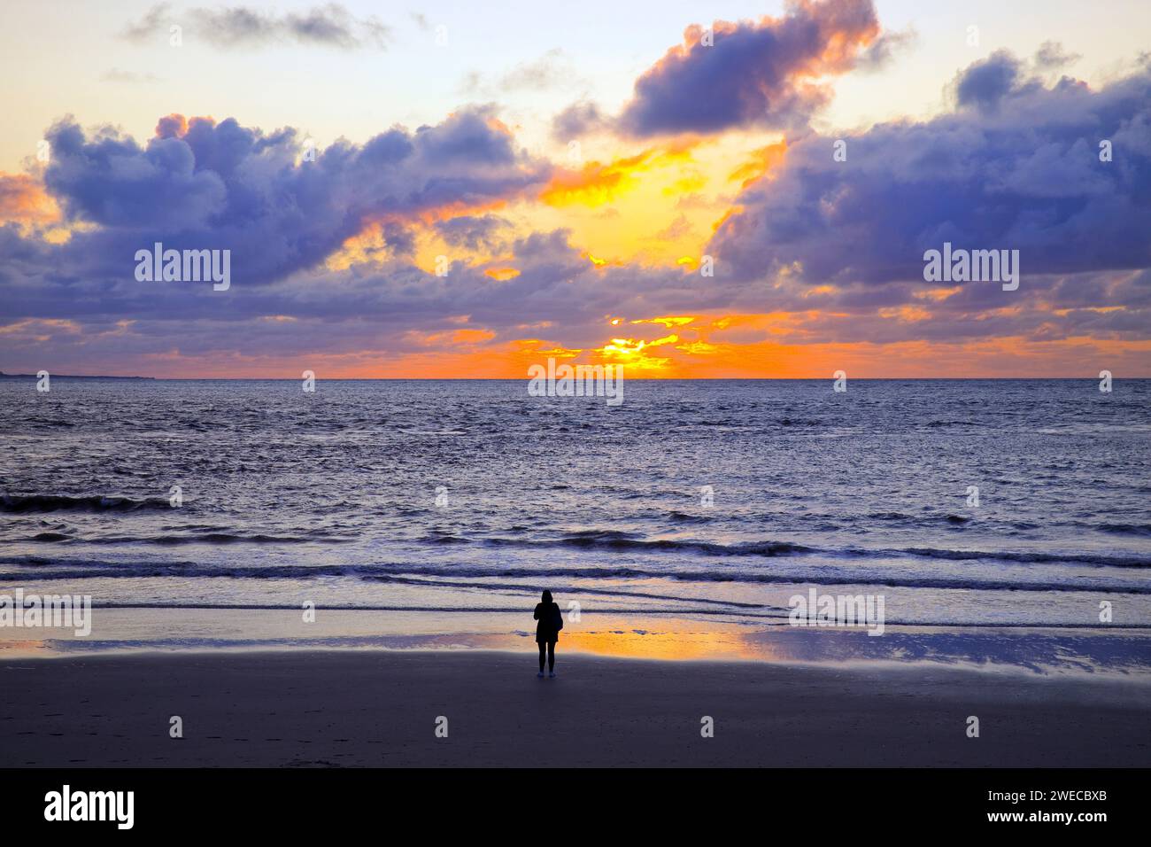 Wadden landscape with setting sun and a person by the sea, Germany, Lower Saxony, Norderney Stock Photo