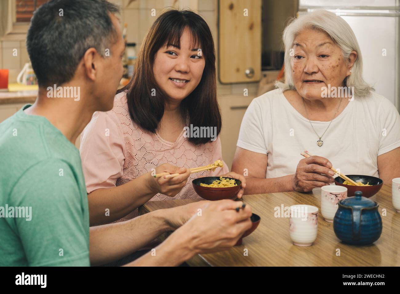 Elderly Japanese Mother with adult children having lunch at home. Concept of family, tradition and ethnic diversity. Stock Photo