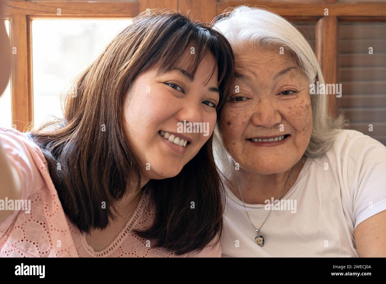 Japanese elderly woman with white hair and daughter smiling taking a selfie Stock Photo