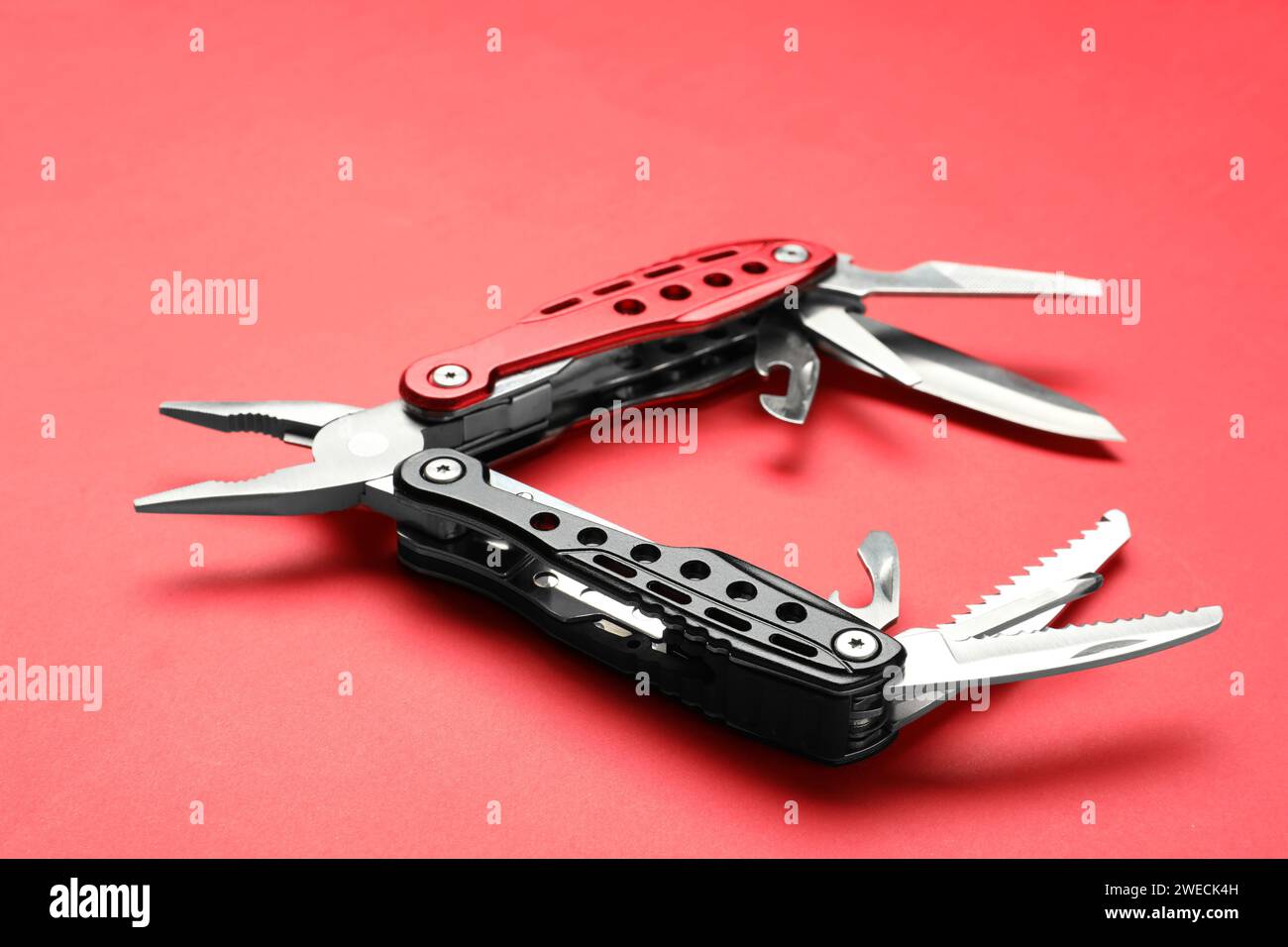 Compact portable multitool on red background, closeup Stock Photo