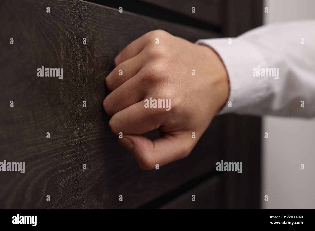 Collector knocking on door indoors, closeup view Stock Photo